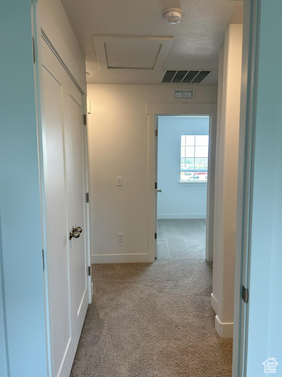 Hall featuring carpet, attic access, and baseboards