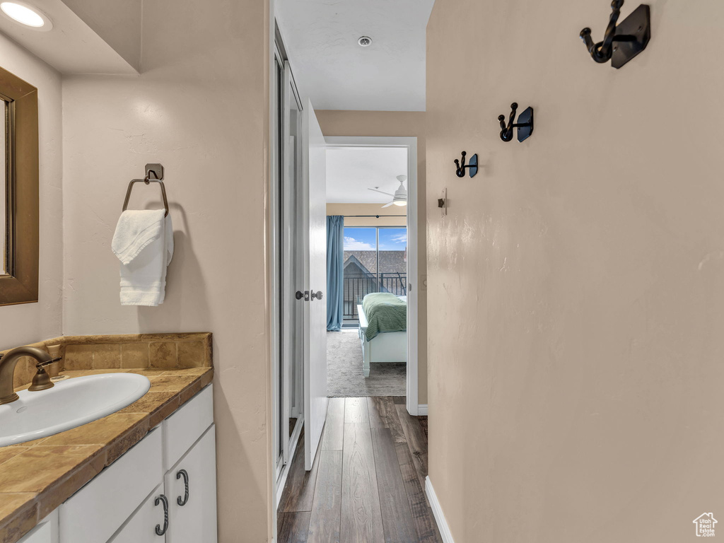 Bathroom with vanity, wood finished floors, ensuite bathroom, and baseboards