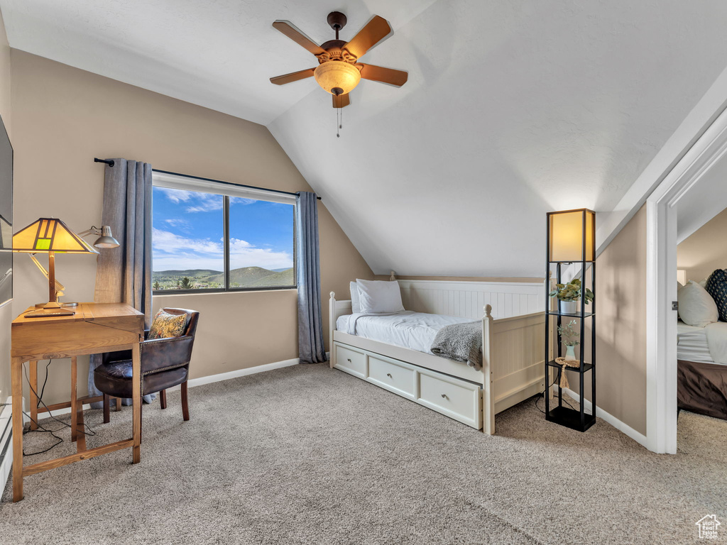 Carpeted bedroom featuring lofted ceiling, baseboards, and ceiling fan