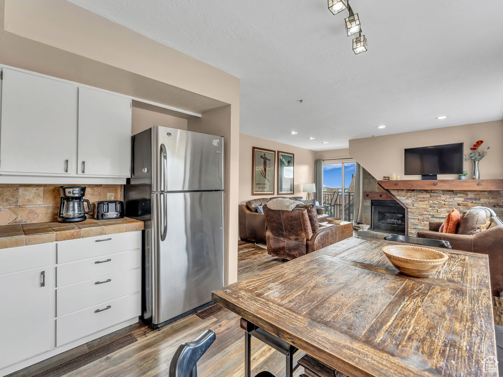 Dining space featuring wood finished floors, a stone fireplace, and recessed lighting