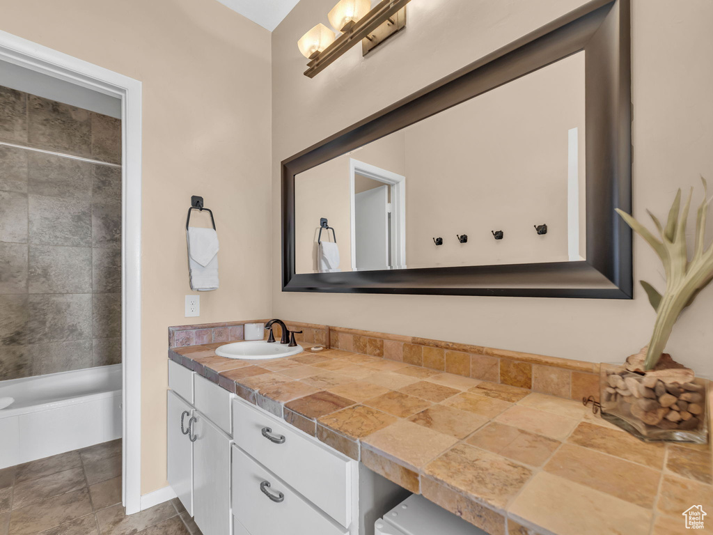 Full bath featuring vanity, stone finish floors, and bathing tub / shower combination