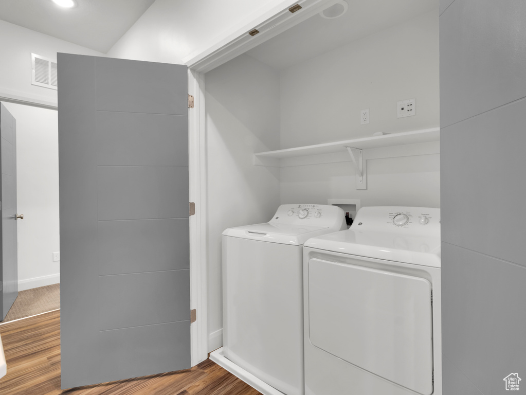 Laundry room featuring washing machine and clothes dryer, wood finished floors, and baseboards
