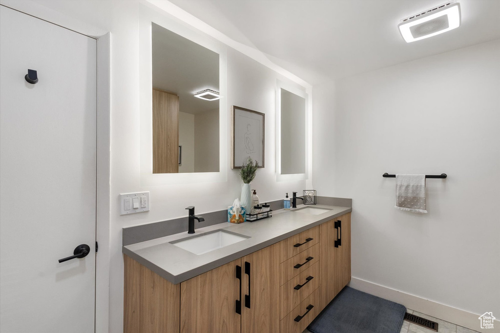 Full bathroom featuring double vanity and baseboards