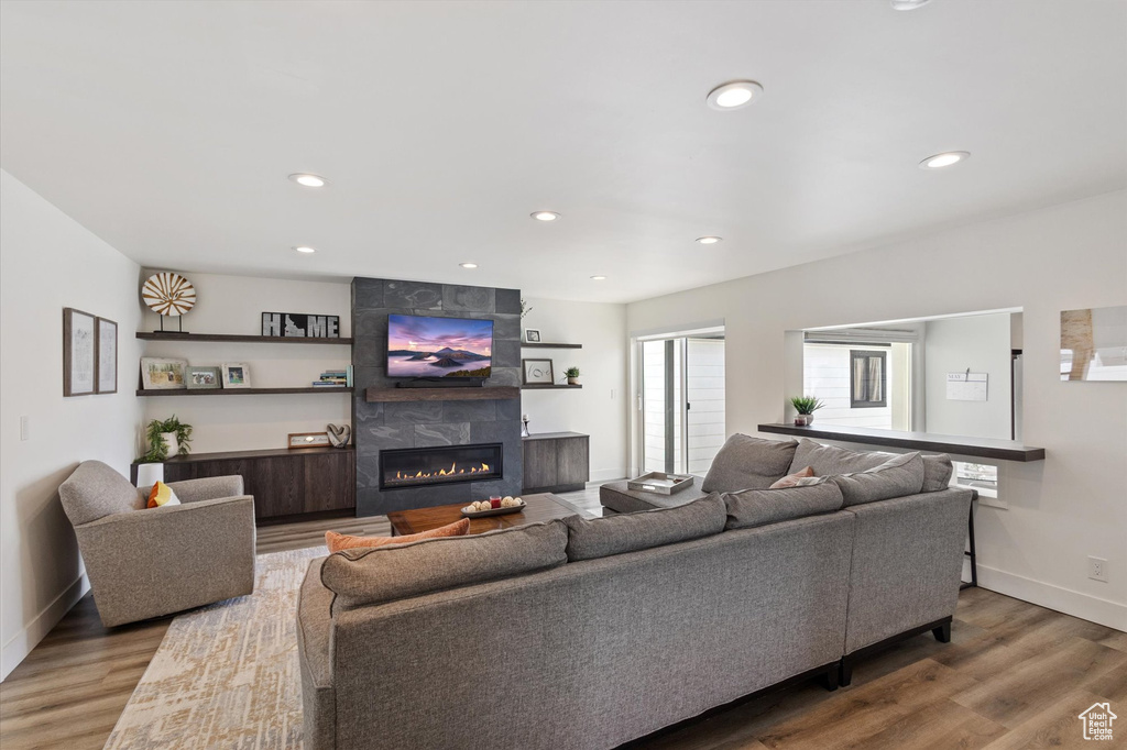 Living area featuring a tiled fireplace, wood finished floors, baseboards, and recessed lighting