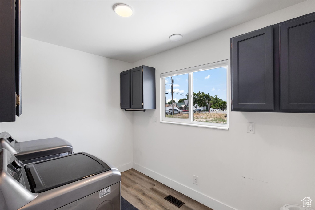 Laundry room with cabinet space, washing machine and dryer, light wood finished floors, and baseboards