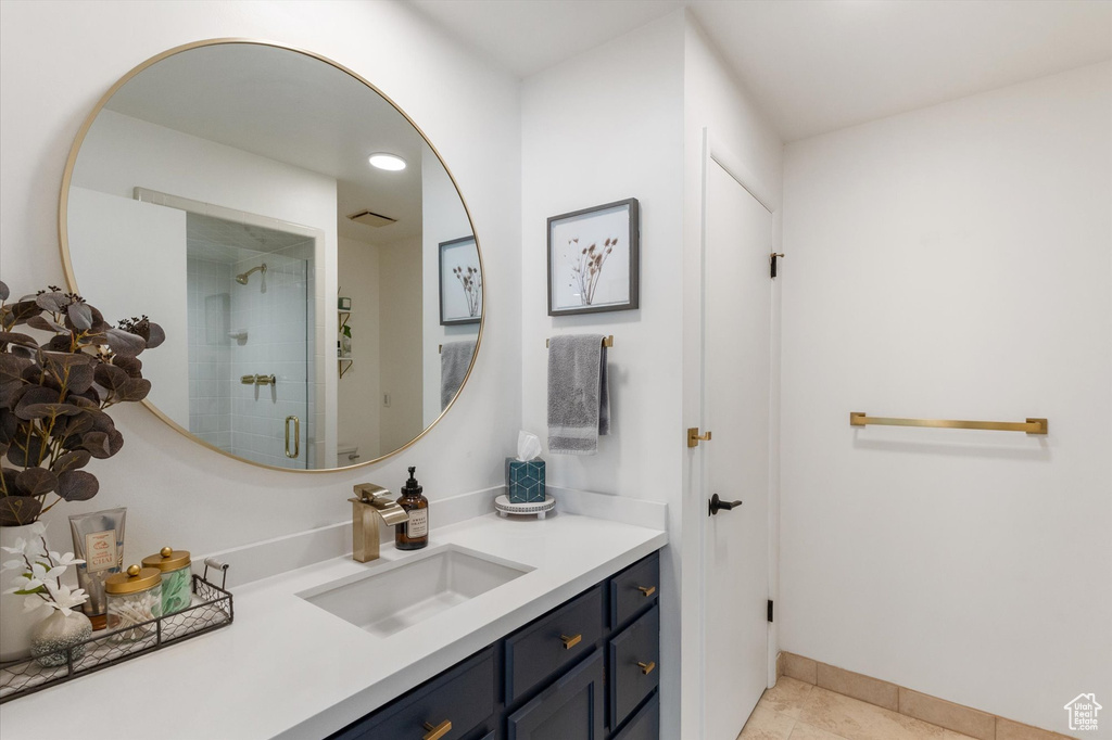 Full bathroom with vanity, a tile shower, and tile patterned flooring