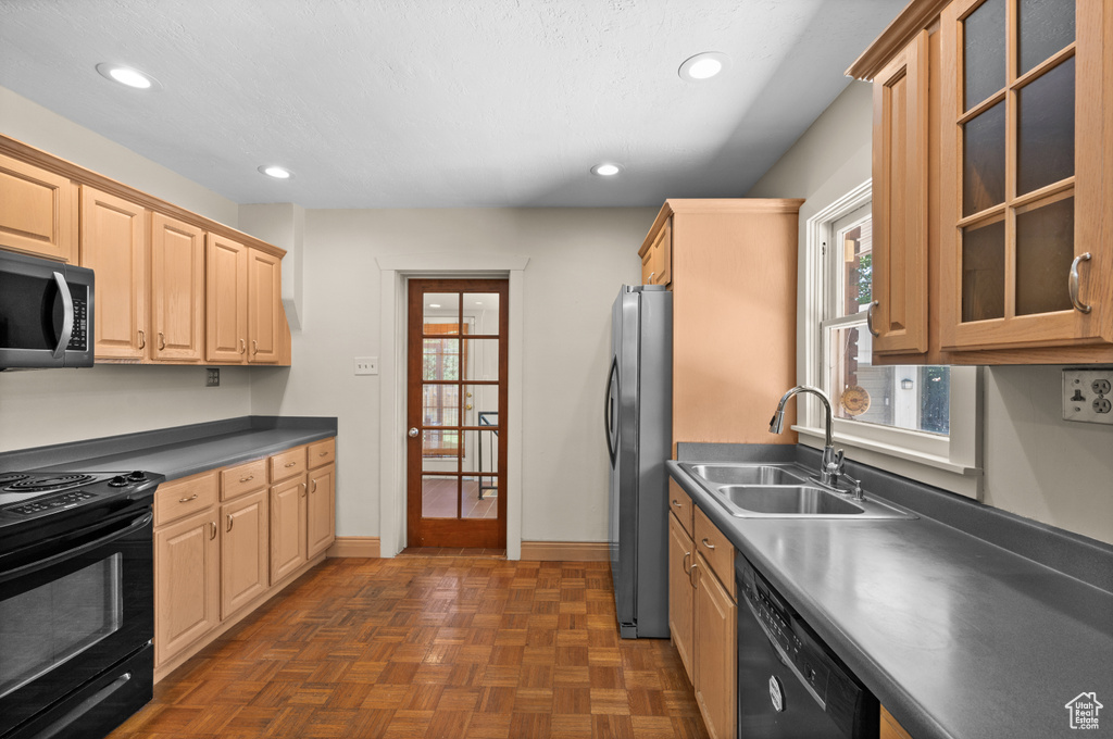 Kitchen with black appliances, a sink, recessed lighting, light brown cabinetry, and glass insert cabinets