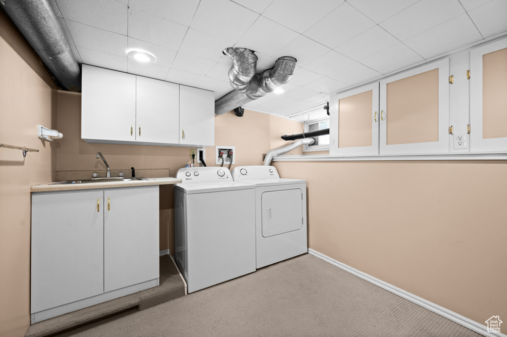 Washroom with cabinet space, washer and clothes dryer, light carpet, and baseboards