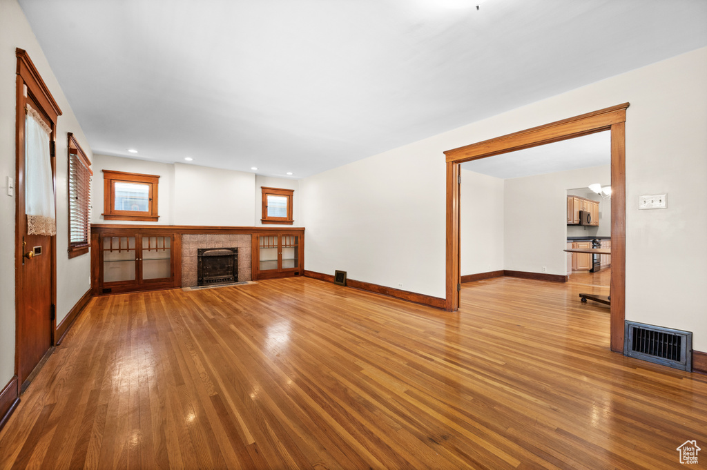 Unfurnished living room featuring wood finished floors, baseboards, and a fireplace
