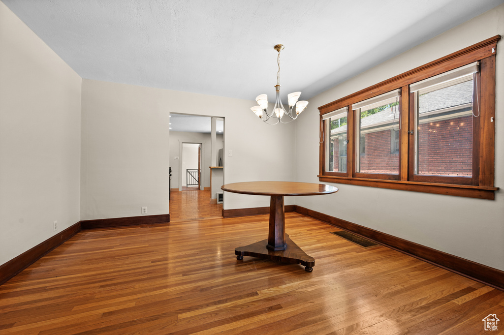 Unfurnished dining area with baseboards, wood finished floors, and a chandelier