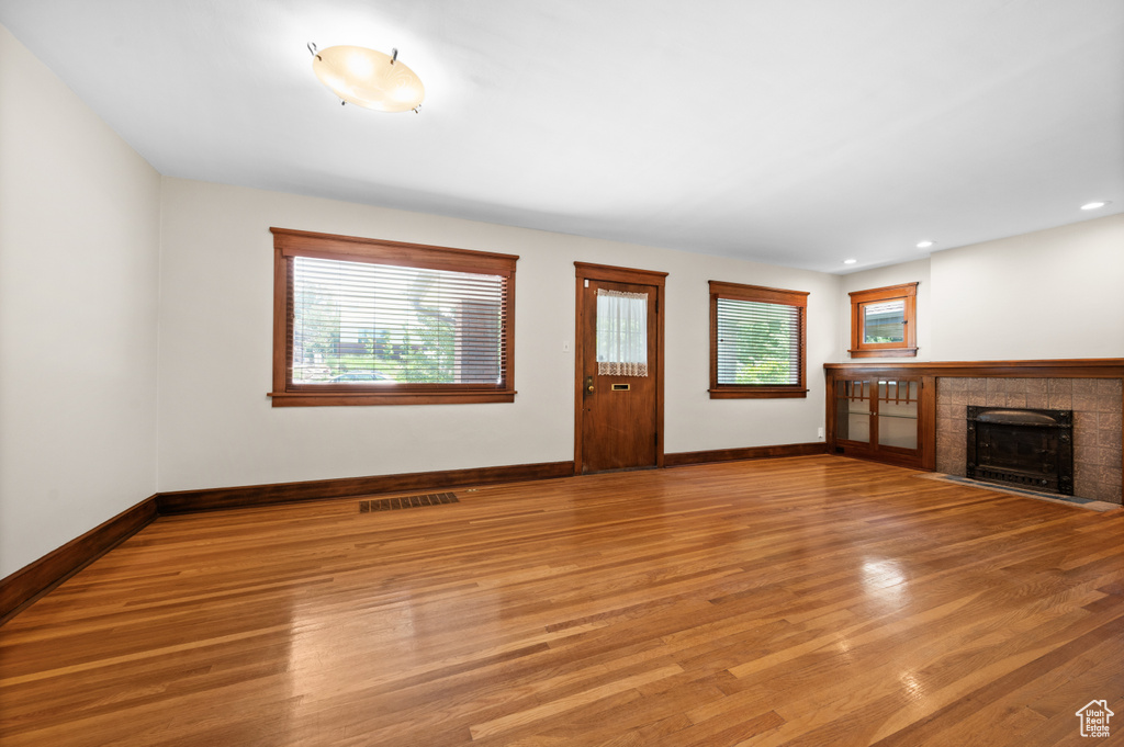 Unfurnished living room with healthy amount of natural light, light wood-style floors, baseboards, and recessed lighting