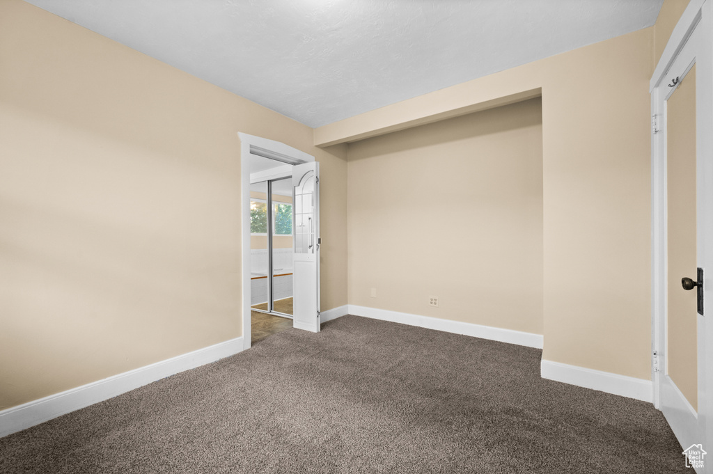 Unfurnished bedroom featuring dark colored carpet, baseboards, and ensuite bath