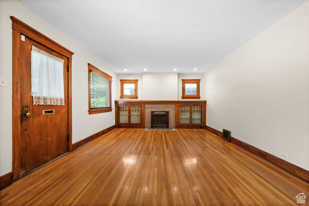 Unfurnished living room featuring light wood finished floors, baseboards, a fireplace, healthy amount of natural light, and recessed lighting