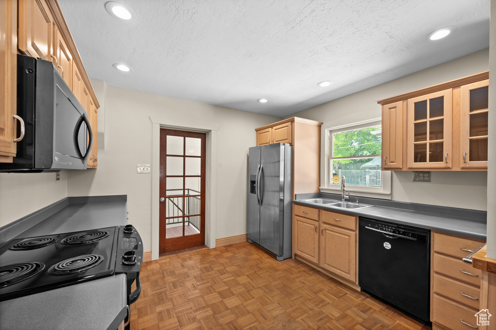 Kitchen featuring dishwasher, stainless steel fridge, range with electric stovetop, a sink, and light brown cabinets