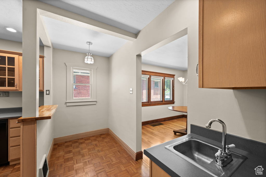 Kitchen with a sink, baseboards, glass insert cabinets, and hanging light fixtures