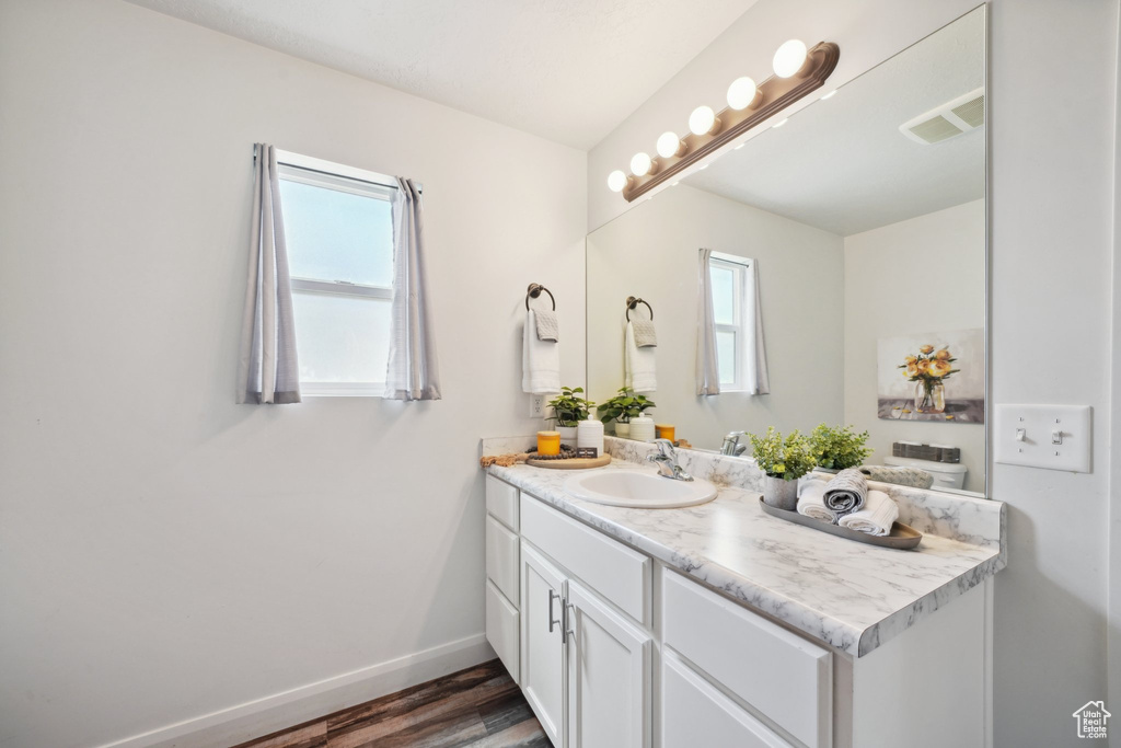 Bathroom featuring vanity, wood finished floors, and baseboards
