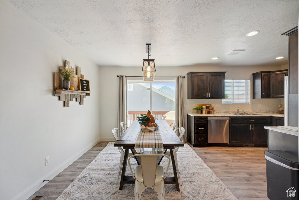 Dining space with a textured ceiling, recessed lighting, baseboards, and light wood-type flooring