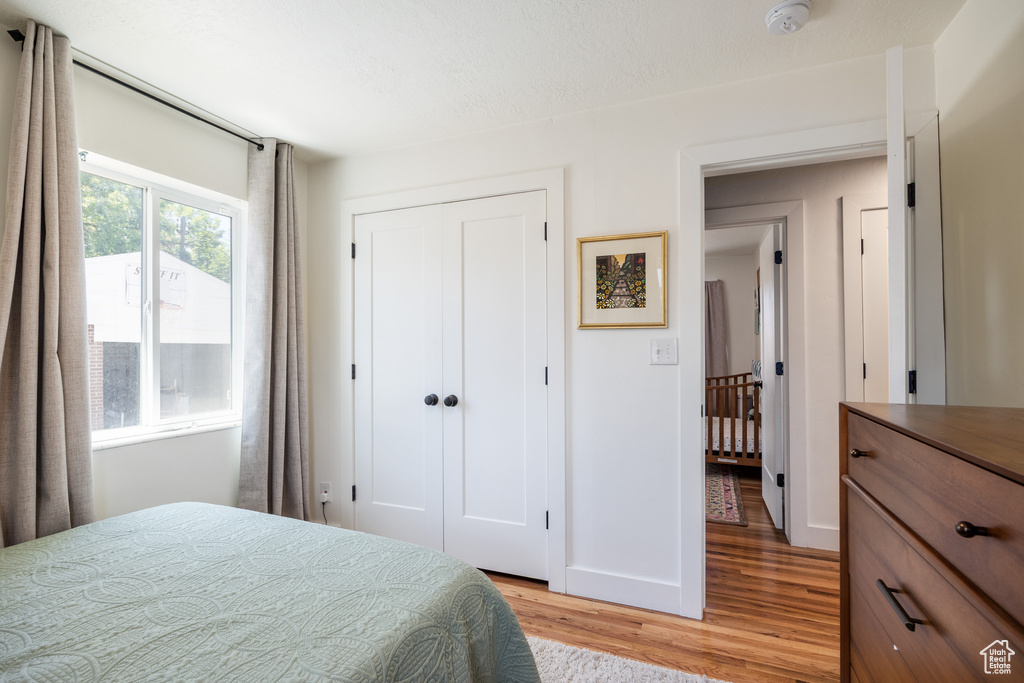 Bedroom with light wood-style floors, a closet, and baseboards