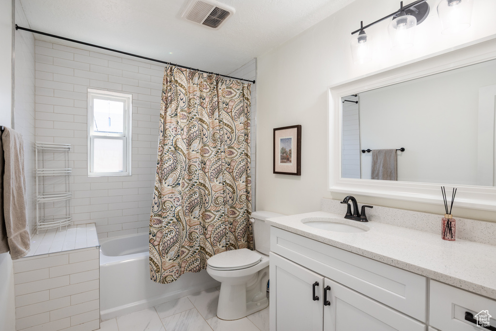 Bathroom featuring vanity, shower / bath combination with curtain, and toilet