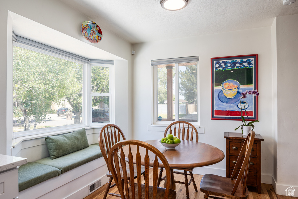 Dining space featuring light wood-style flooring, healthy amount of natural light, baseboards, and a textured ceiling