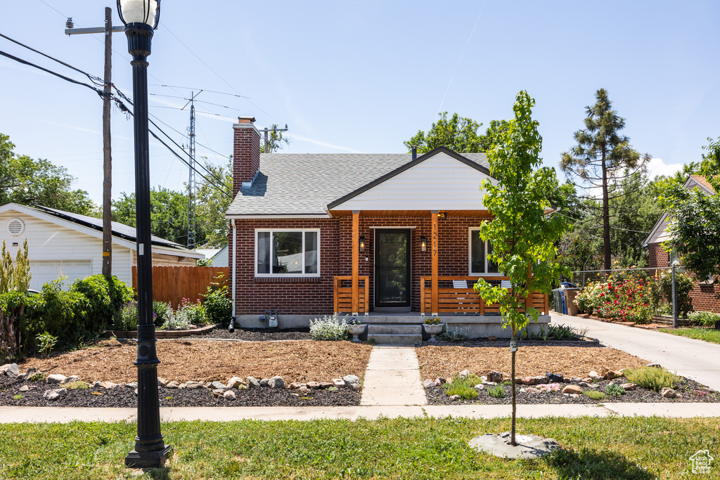 Bungalow-style house with brick siding, covered porch, a chimney, and roof with shingles