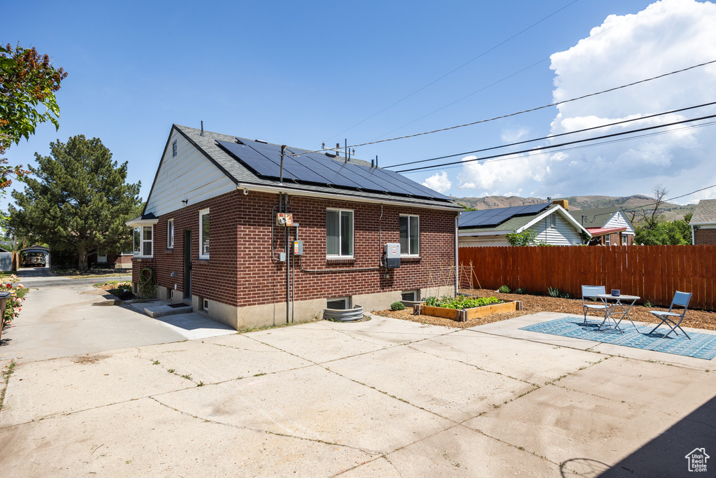 Back of house featuring a patio area, solar panels, and brick siding