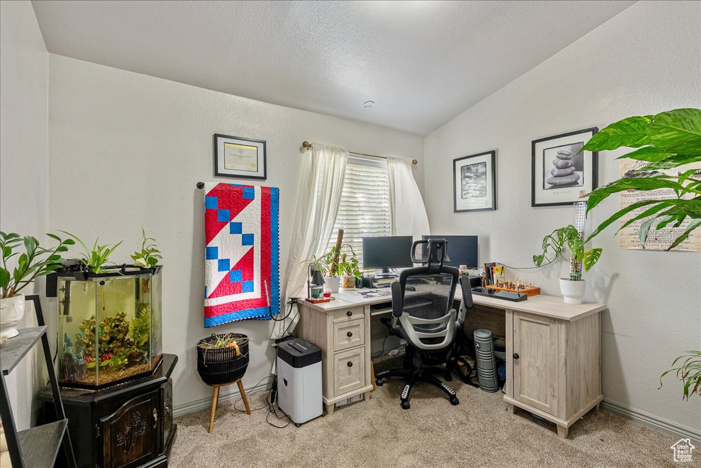 Office area featuring light carpet, vaulted ceiling, and baseboards