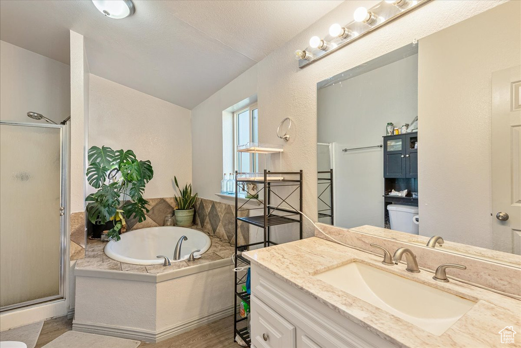 Full bath featuring a stall shower, toilet, a garden tub, vanity, and lofted ceiling