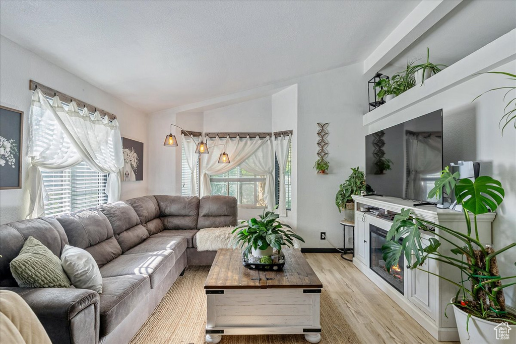 Living area featuring light wood-style floors and a glass covered fireplace