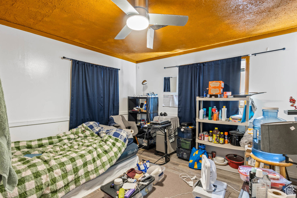 Bedroom with wood finished floors, a ceiling fan, and crown molding