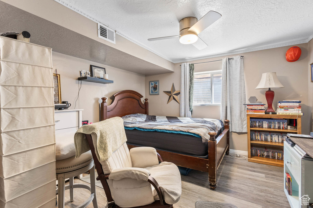 Bedroom with wood finished floors, a textured ceiling, and a ceiling fan