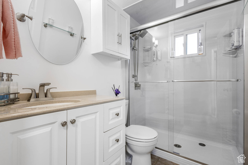 Bathroom featuring toilet, vanity, and a shower stall