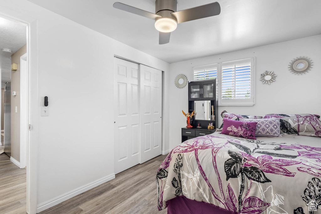 Bedroom with light wood-type flooring, a closet, baseboards, and a ceiling fan