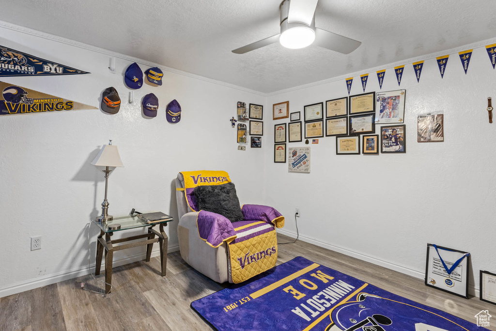 Living area with wood finished floors, ceiling fan, a textured ceiling, and baseboards
