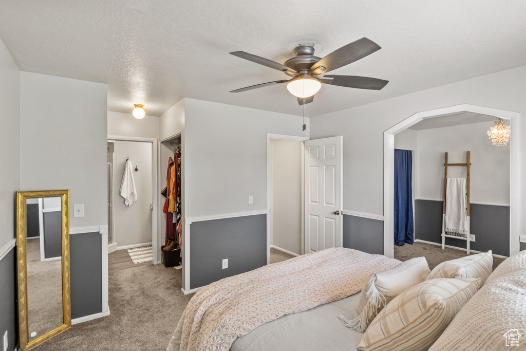 Carpeted bedroom featuring a spacious closet, a closet, baseboards, and ceiling fan