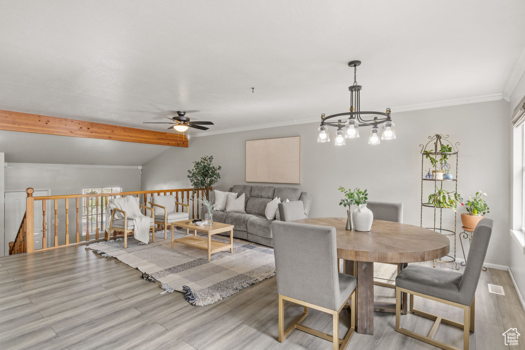 Dining space with wood finished floors, a ceiling fan, plenty of natural light, crown molding, and a chandelier