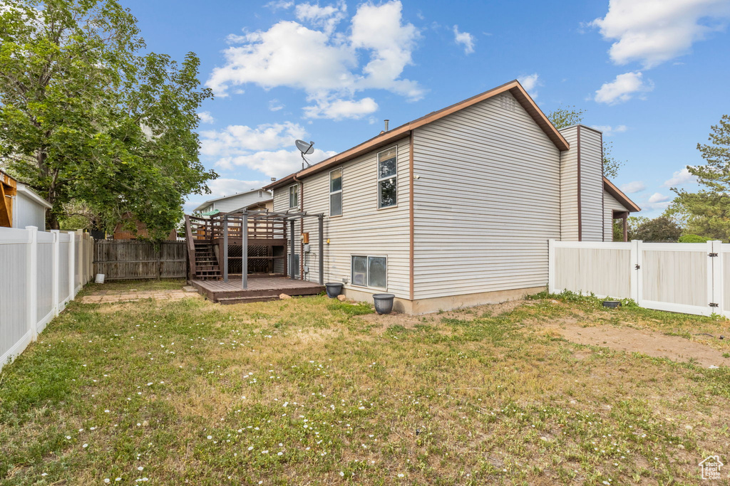 Rear view of house with a wooden deck and a gate