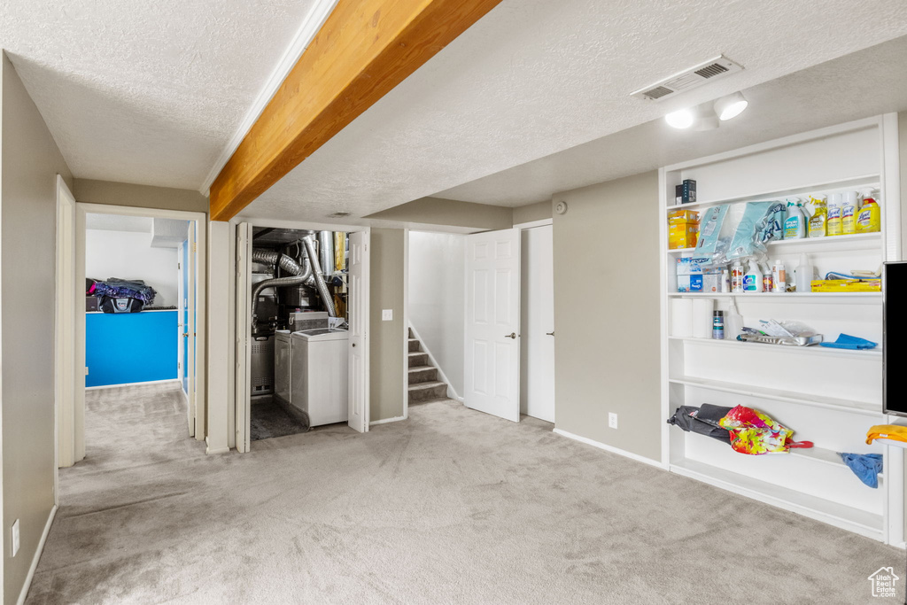 Finished below grade area with a textured ceiling, carpet flooring, independent washer and dryer, baseboards, and stairs