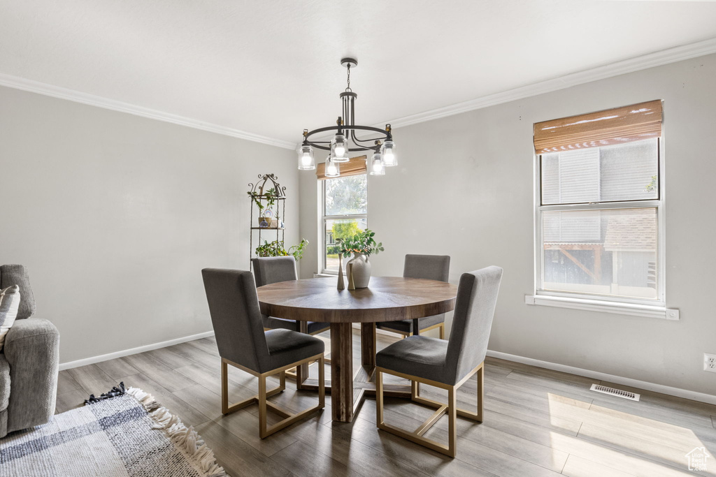 Dining room featuring crown molding, a chandelier, baseboards, and wood finished floors