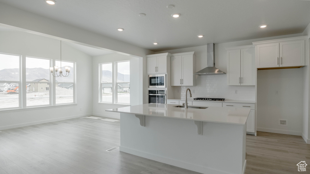 Kitchen featuring wall chimney exhaust hood, stainless steel oven, a sink, built in microwave, and black gas stovetop