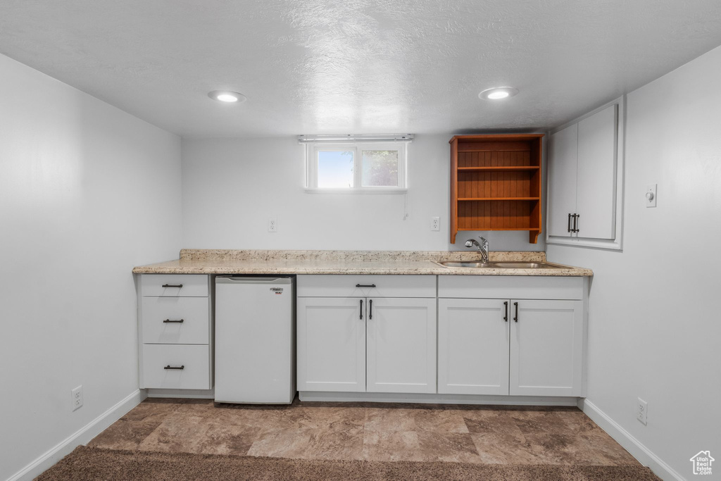 Kitchen featuring a sink, open shelves, baseboards, fridge, and recessed lighting