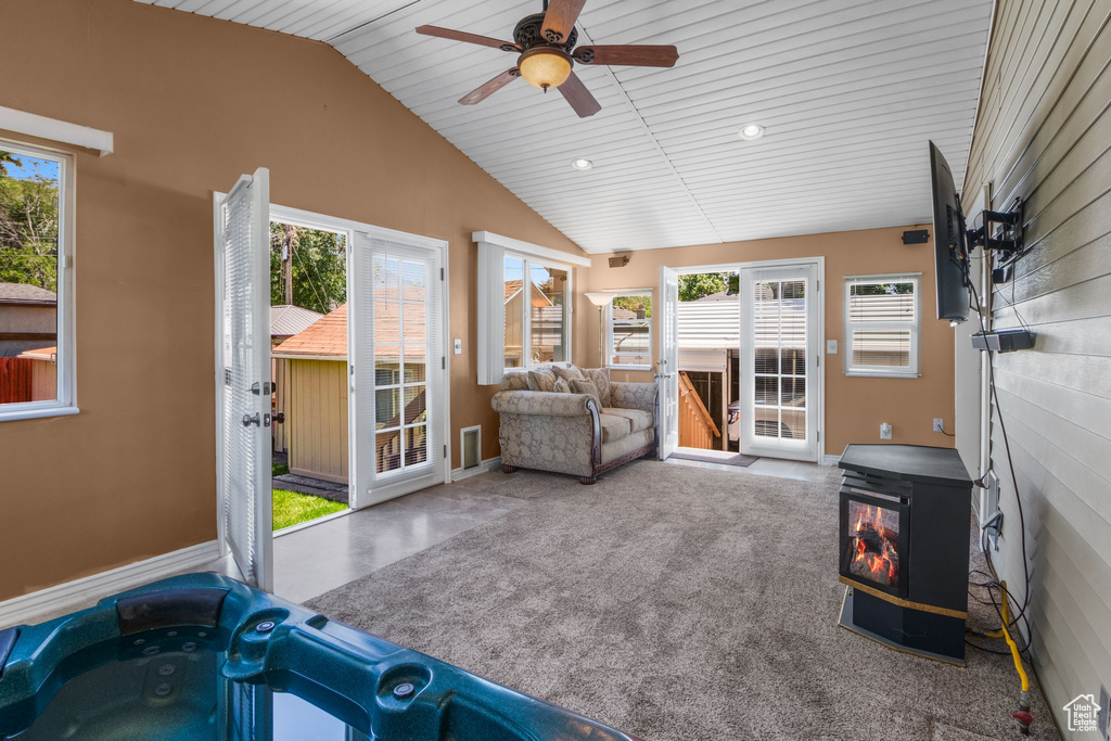 Sunroom / solarium with a wood stove, plenty of natural light, lofted ceiling, and a hot tub
