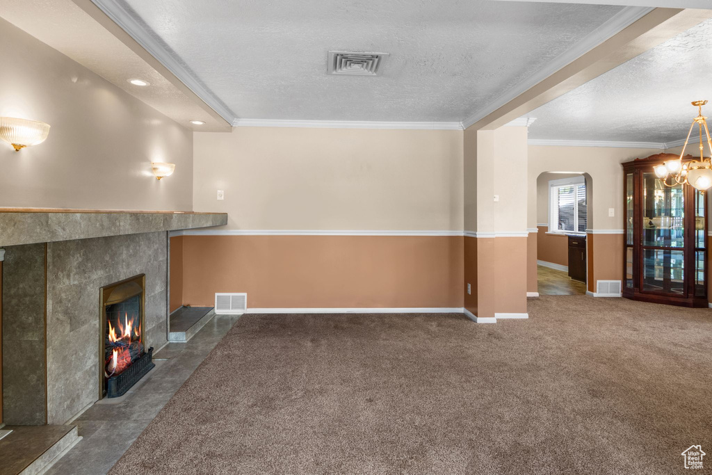 Unfurnished living room featuring a textured ceiling, a fireplace, arched walkways, baseboards, and crown molding