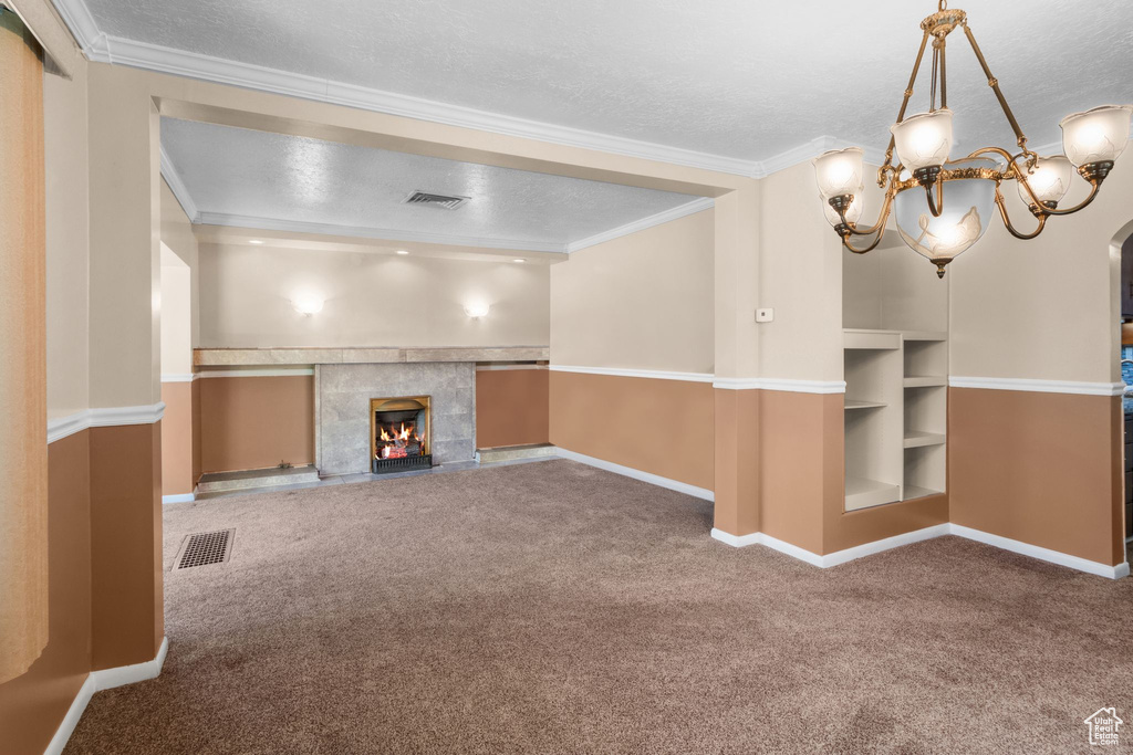 Unfurnished living room with carpet flooring, baseboards, a chandelier, crown molding, and a fireplace