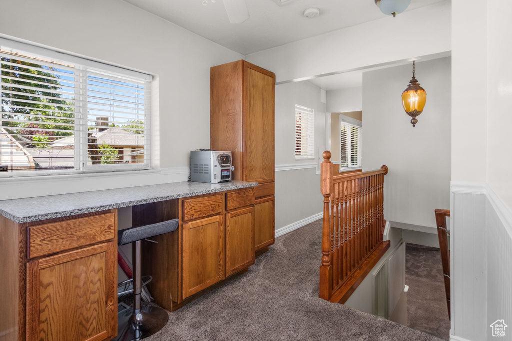 Office area featuring dark carpet, healthy amount of natural light, built in study area, and ceiling fan