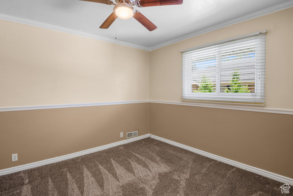 Carpeted empty room featuring baseboards, ceiling fan, and ornamental molding