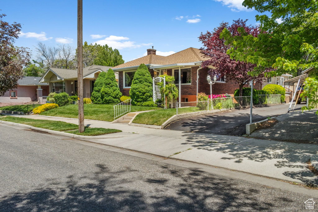 View of front of property featuring a chimney, brick siding, and asphalt driveway
