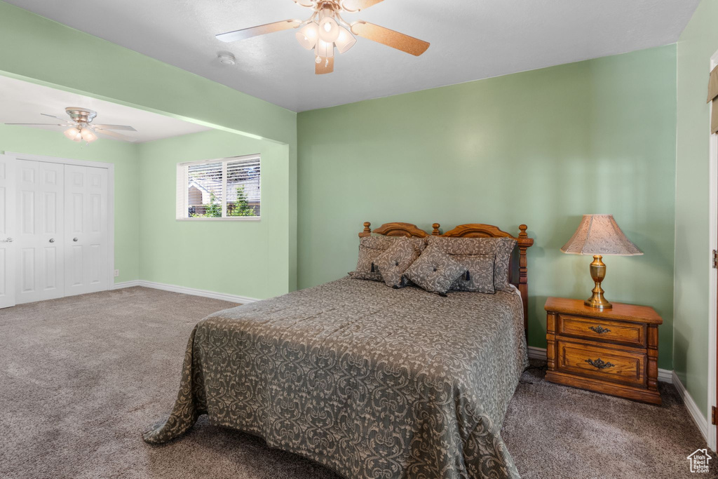 Carpeted bedroom featuring baseboards, a ceiling fan, and a closet