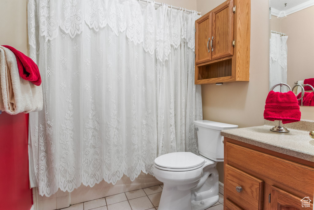 Full bathroom with vanity, toilet, tile patterned flooring, ornamental molding, and a shower with curtain