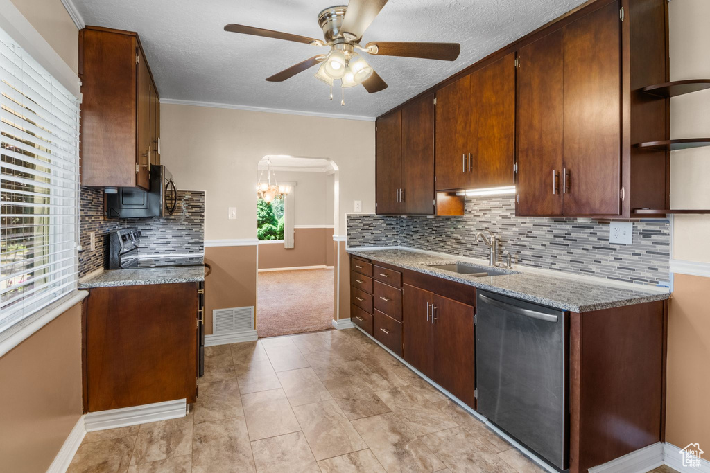 Kitchen with a sink, appliances with stainless steel finishes, ceiling fan, arched walkways, and decorative backsplash
